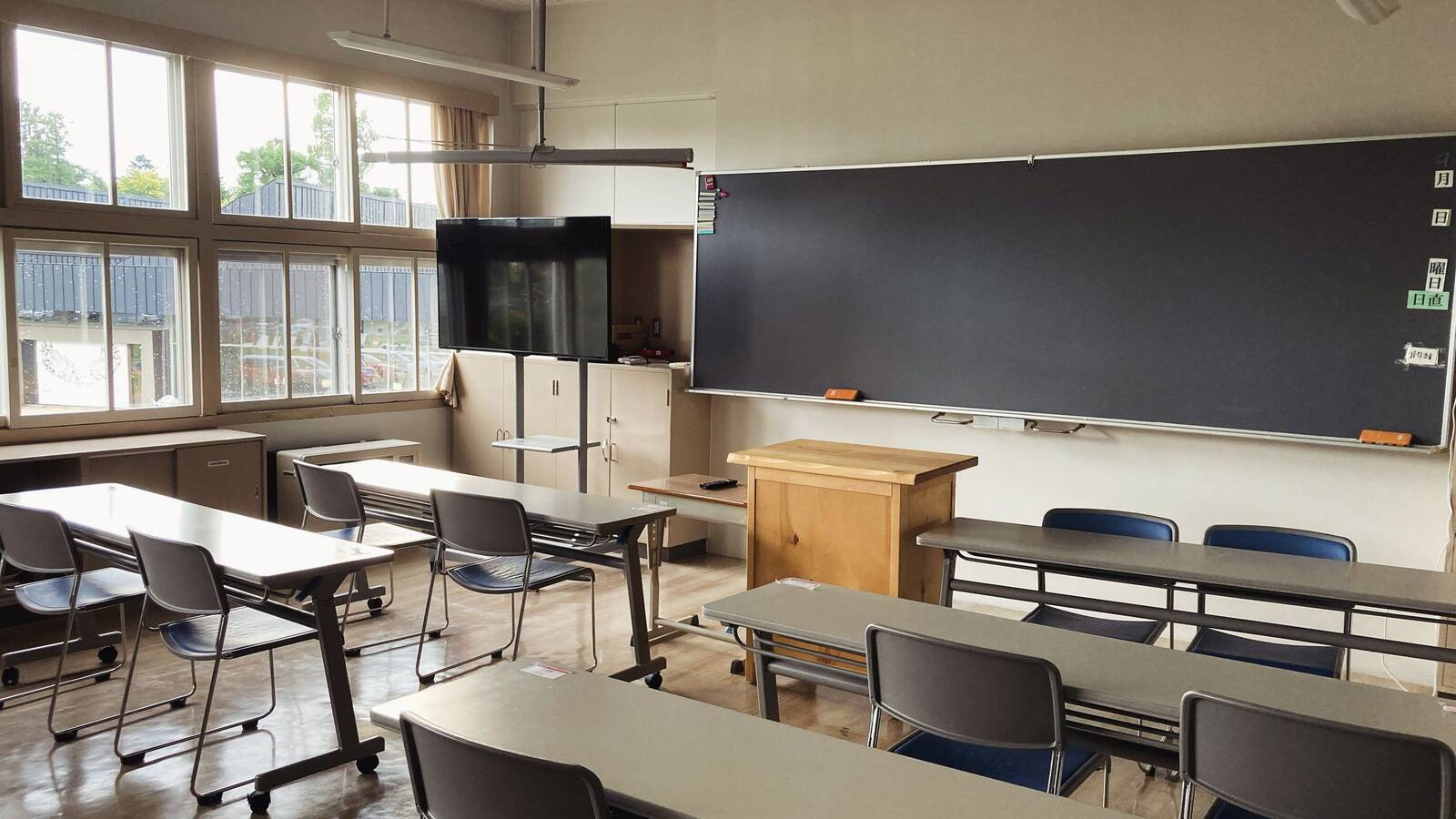 An empty classroom in Asahikawa, Japan, with rows of desks, a large blackboard and tall windows