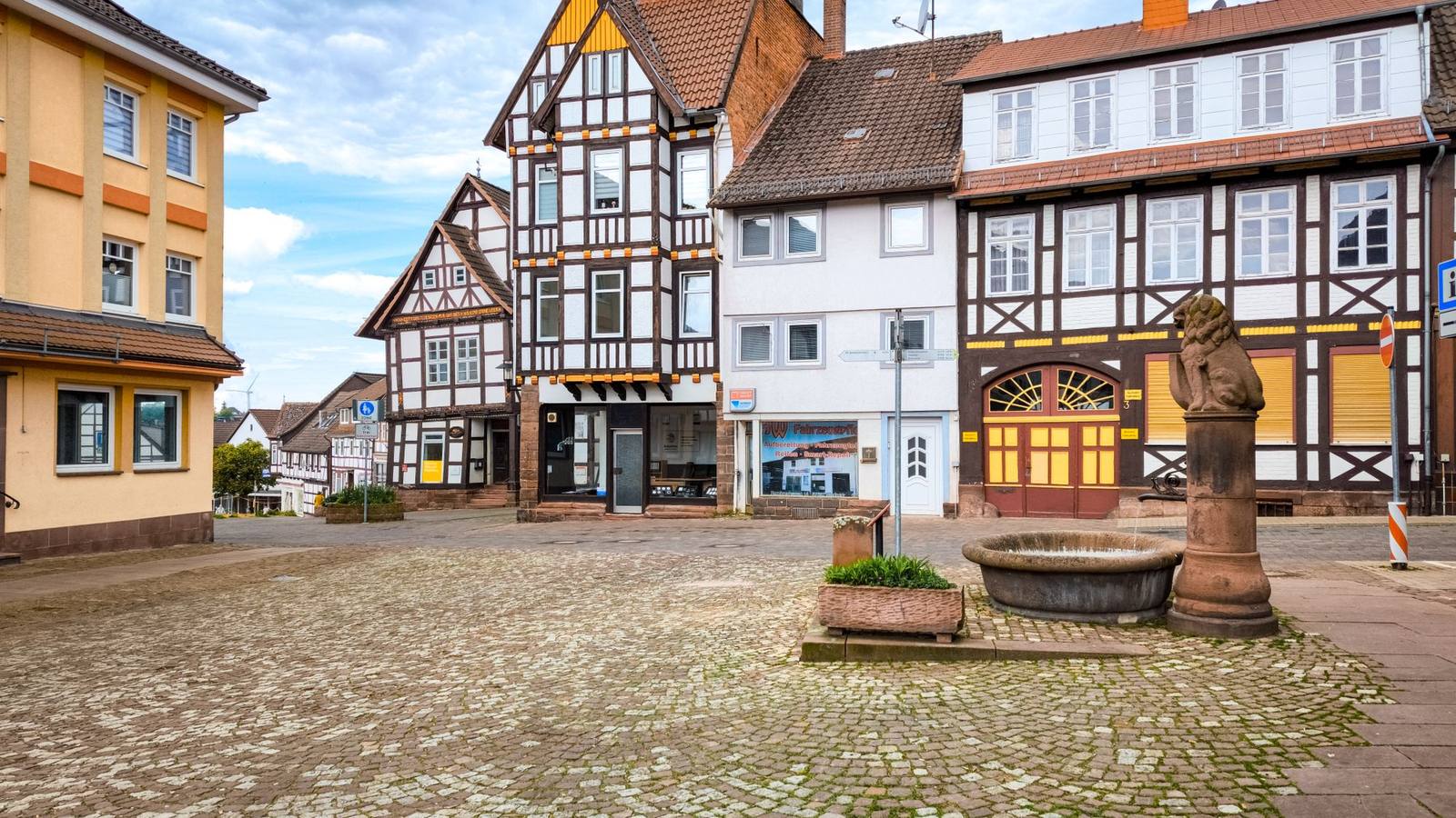 A quiet cobblestone square surrounded by traditional European buildings.