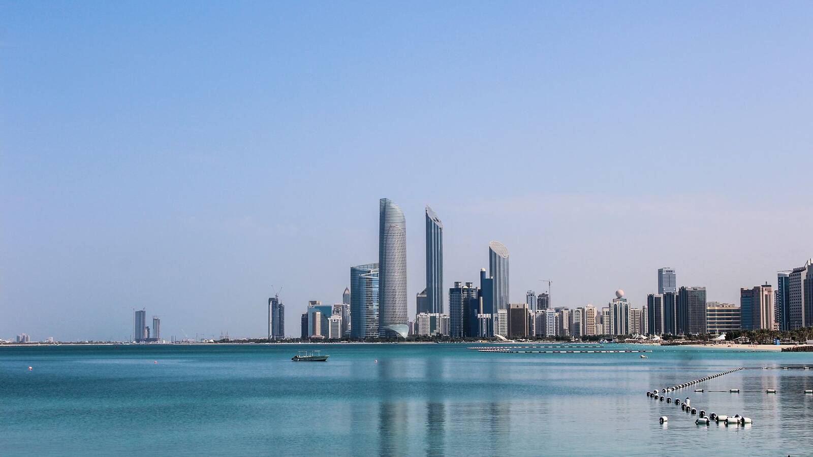The Abu Dhabi skyline across calm blue water on a clear day